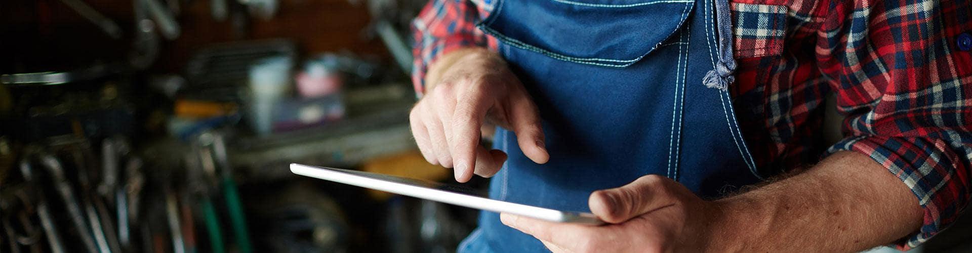 Cobros Autónomos - Un hombre con camisa de cuadros está utilizando su tableta digital.