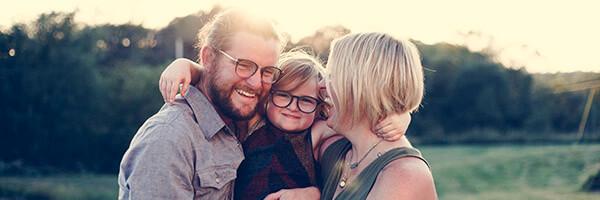 Seguro de Vida - Familia felices mientras que sonríen y se abrazan en el campo