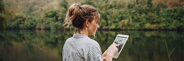 Préstamo Joven In - Una mujer usando una tableta digital en plena naturaleza