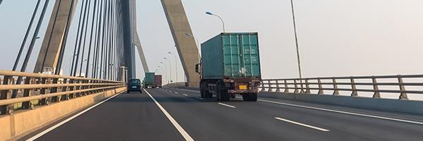 Seguro de Transportes - Carretera de una ciudad donde circulan camiones de transporte de mercancias junto a un puente