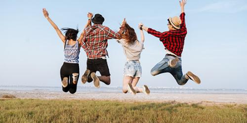 Promoción Cambiar cuenta - Jóvenes felices y sonriendo saltando en el aire frente a la playa